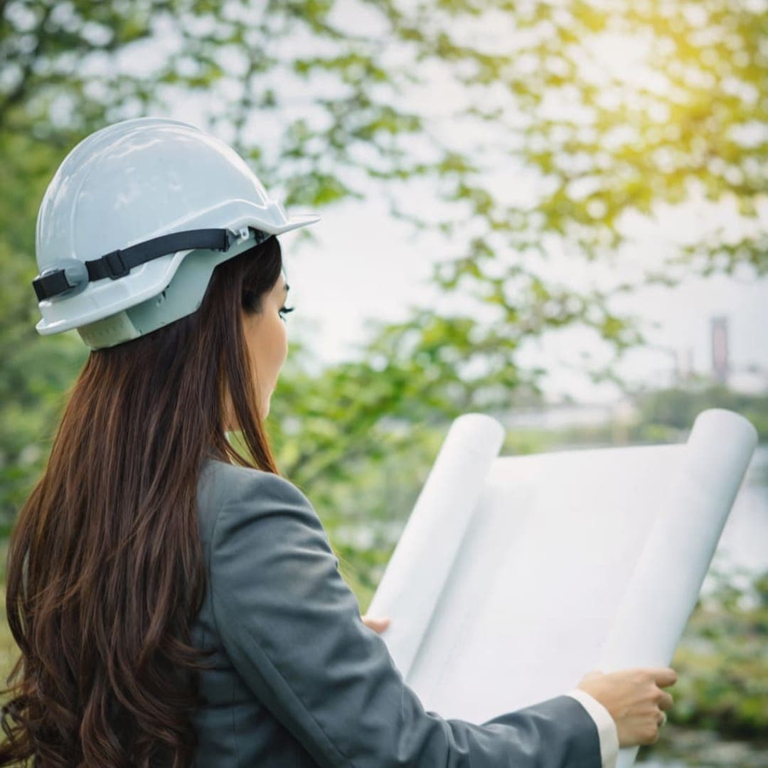 Consultora ambiental com capacete analisando um projeto técnico ao ar livre.